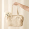 Beige tote bag with a white teddy bear inside, held by a hand against a light background